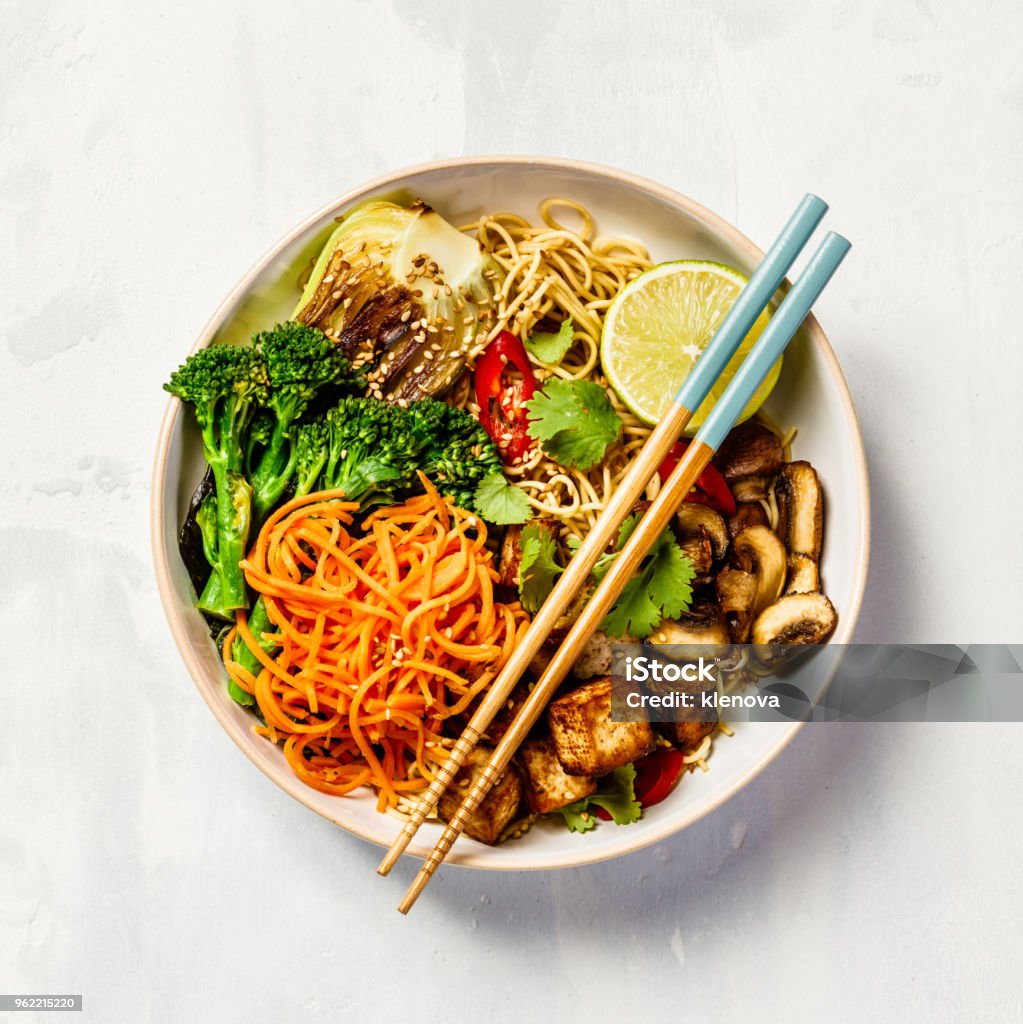 Asian Tofu Soba Noodle Bowl Vegetarian noodles with tofu, broccoli, mushrooms, carrot, bok choy on white stone table. Top view, flat lay, copyspace Asia Stock Photo