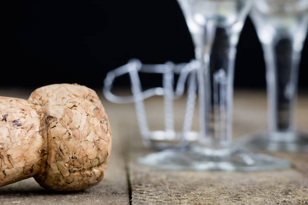 Cork from champagne on a wooden kitchen table. Good New Year's drinks and great fun. Dark background.