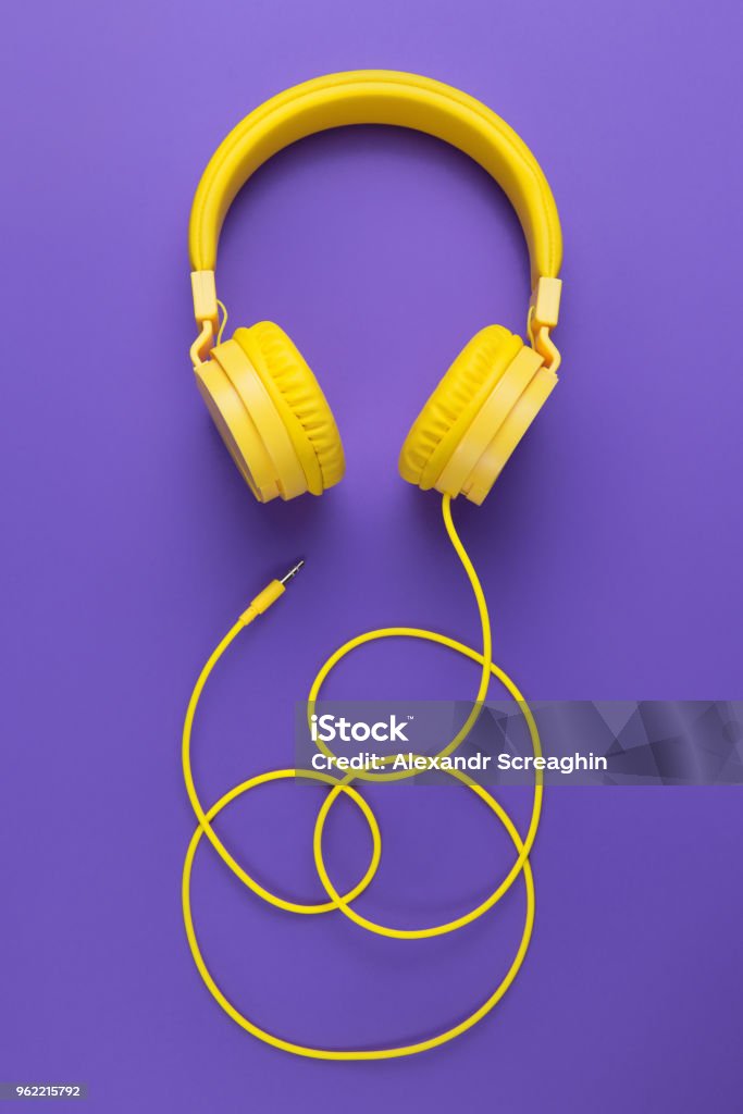Yellow headphones on purple background. Music concept. Yellow headphones on purple background. Music concept Headphones Stock Photo