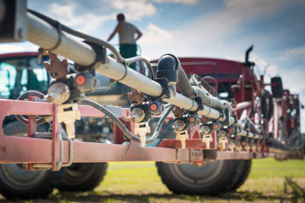 düsen auf das düsenrohr, vor dem hintergrund der spritze und die person auf dem lauf beim betanken - spraying agriculture farm herbicide stock-fotos und bilder