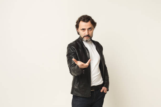 Casual man with outstretched hand over white background Middle-aged man with outstretched hand with open palm. Portrait of harsh guy in leather jacket over white studio background, copy space. Inviting gesture male is standing and shows outstretched hand with open palm stock pictures, royalty-free photos & images
