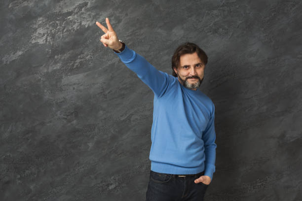 istock Lucky man showing victory sign at gray background 962218974