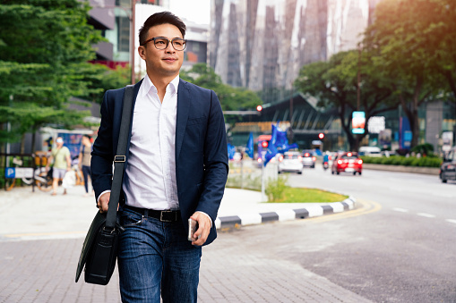 Young chinese businessman walking along the street in downtown Kuala Lumpur. Kuala Lumpur, Malaysia, Asia