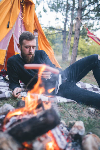 istock hiking man prepare tasty sausages on campfire 962220456
