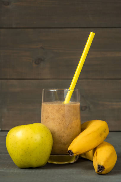 Bananas, green apple and a glass with fresh smoothies and straws