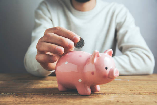 istock Man putting coin in piggy bank 962226872