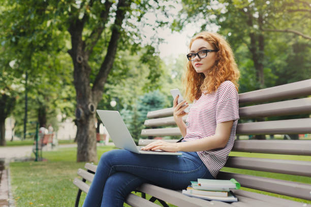 Serious woman is using laptop in the park