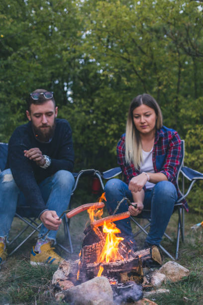 istock Happy couple fried sausages on bonfire in the forest 962229764