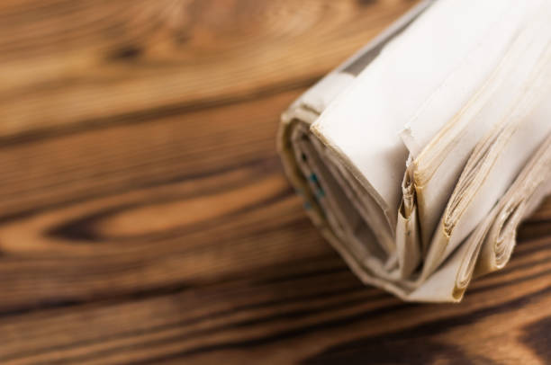 Roll of old newspapers on old brown wooden table with copy space for your text