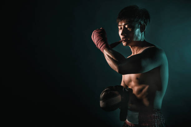 asian male tighten up his boxing gloves with his lips asian male tighten up his boxing gloves with his lips Boxing stock pictures, royalty-free photos & images