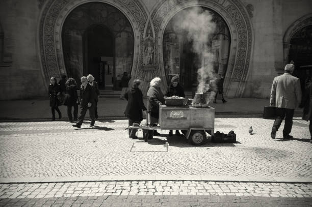 Lisbon, Portugal - April 5, 2016: A traditional roasted chestnut seller attends clients in front of the Rossio Train Station in Lisbon downtown.