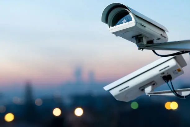 Focus on security CCTV camera monitoring system with panoramic view of a city on blurry background