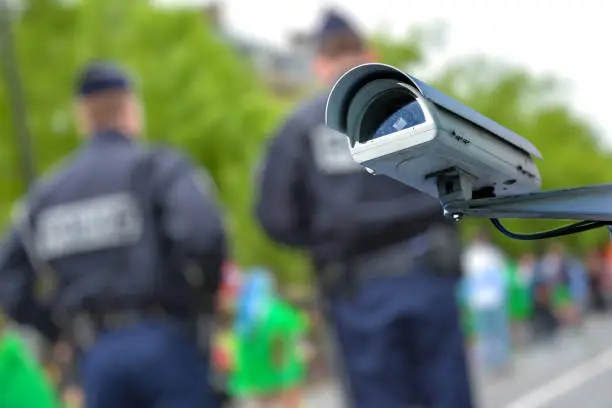 Focus on security CCTV camera or surveillance system with police officers on blurry background