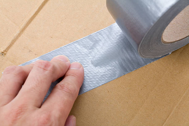 A hand holding on to silver duct tape