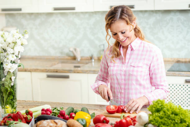 istock smiling woman is slicing tomatoes on a kitchen table 962264126