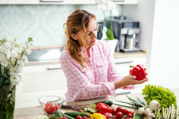 istock smiling woman eats red pepper in the kitchen 962264258