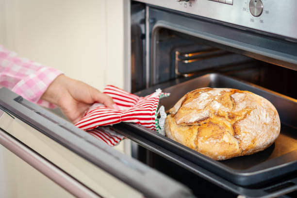 woman's hand takes out the fragrant bread from the oven woman takes out fragrant and crunchy bread from the oven in the kitchen girls getting ready to go out stock pictures, royalty-free photos & images