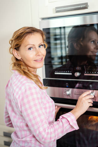 istock woman turning on the oven in the kitchen 962264338