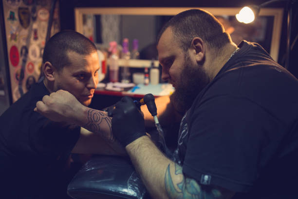 istock Tattoo artist tattooing mans forearm 962268086