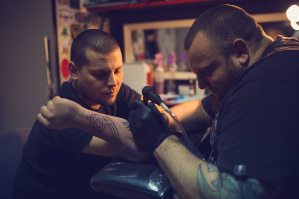 istock Tattoo artist tattooing mans forearm 962268124