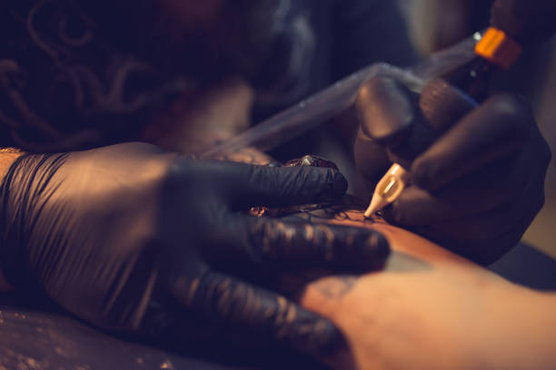 Tattoo artist at work A photo of artist making tattoo on man's hand.Tattoo expert is working in studio. arm tattoo ideas for men pictures stock pictures, royalty-free photos & images
