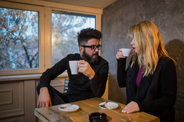 istock Happy young couple is drinking coffee and smiling while sitting at the cafe 962270918