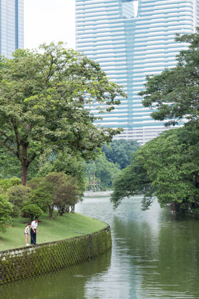 A young girl fishes with her grandfather in the lake at the public park