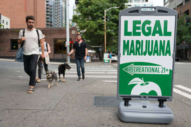 Legal Marijuana Seattle, USA - July 14, 2016: People passing a State Legal Marijuana shop sign on 2nd avenue late in the day in downtown. legalization photos stock pictures, royalty-free photos & images