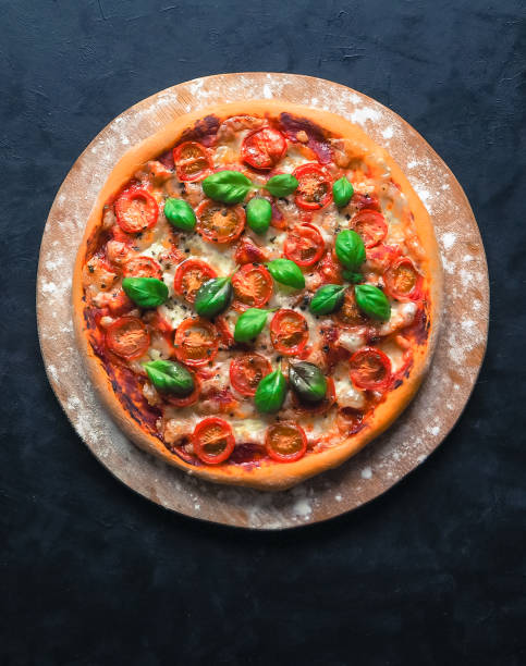 Pizza margherita on the chalk board with copy space on the black table.
