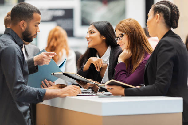 Business people attending an exhibition A small group of business people working at a standing desk in the exhibition hall exhibition stock pictures, royalty-free photos & images