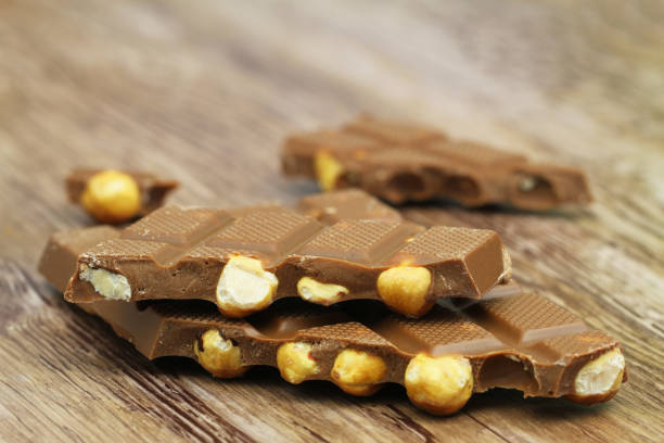 istock Pieces of milk chocolate with whole hazelnuts on wooden surface 962300582