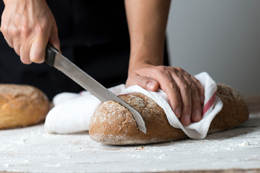 Young woman cutting freshly made bread.