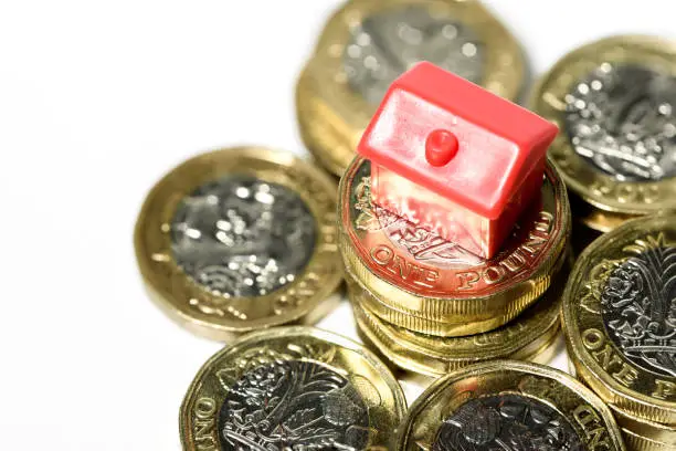 Photo of Macro close up of a Miniature house resting on new pound coins