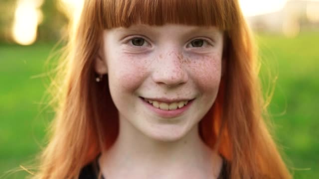 Close-up face of happy ginger girl with freckles on blurred background