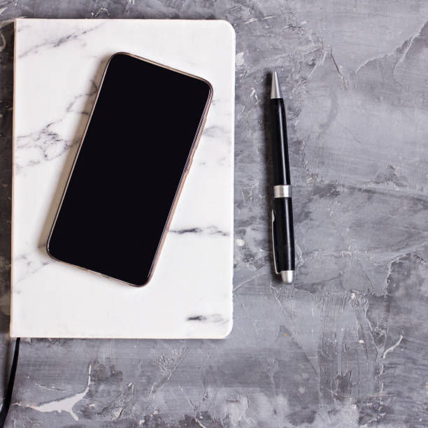 istock Notepad, mobile phone, pen, succulent, glasses, cup of coffee on a gray cement background. 962309688
