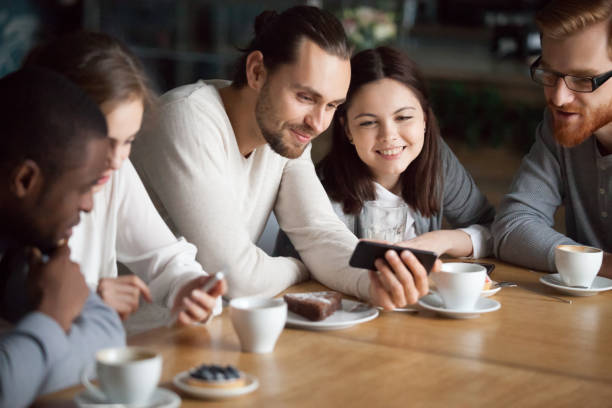 istock Diverse friends having fun using smartphones hanging together in cafe 962315296