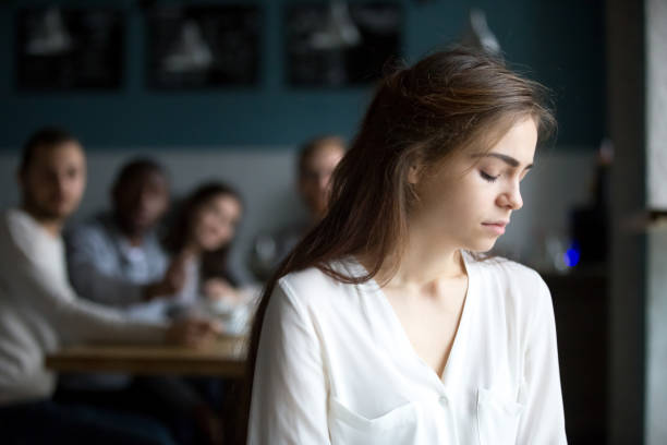 Sad young woman avoiding friends suffering from gossiping or bullying Sad young woman avoiding ignoring bad friends suffering from gossiping, bullying, unfair attitude or discrimination, frustrated millennial girl feeling upset, hurt and offended sitting alone in cafe prejudice stock pictures, royalty-free photos & images