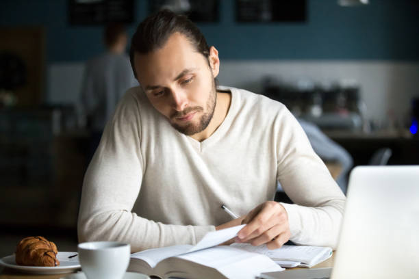 istock Serious student reading book preparing for exam studying in cafe 962315486