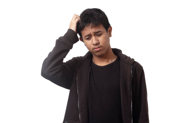 Young thoughtful asian indonesian guy looking down on isolated white background stock photo