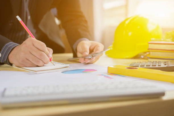 istock Architects working on blueprint with pencil,engineer inspective in workplace ,architectural project, blue prints,ruler,calculator,laptop and yellow helmet. Construction concept. Engineering tools 962320626