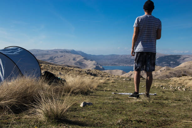 istock Man standing next to a tent and looking at amazing view 962322402