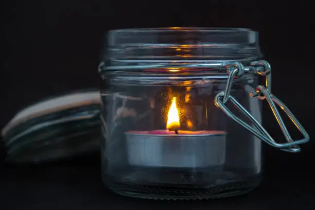 candle in a glass jar on a black background