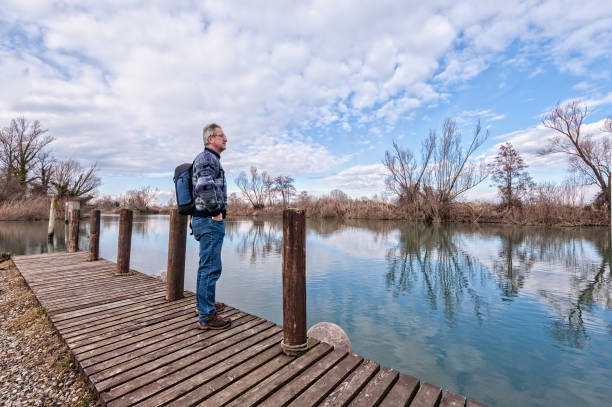 istock Hiker with backpack over wood pier on shore of river. 962326712