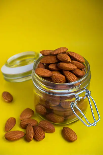 nuts almonds in a glass jar on a yellow background