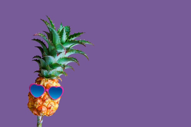 istock Minimal summer concept of pineapple and sunglasses on violet background with copy space 962327094