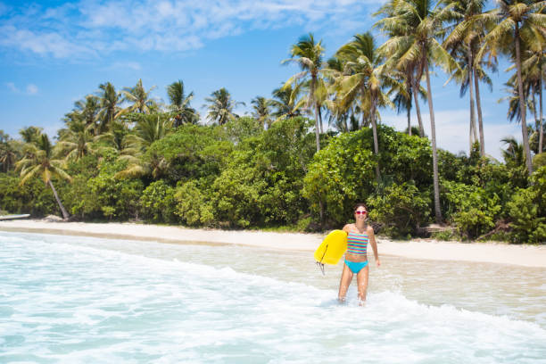 istock Young woman with surf board on tropical beach 962338904