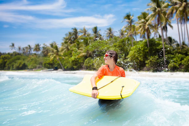 istock Child surfing on tropical beach. Surfer in ocean. 962344730
