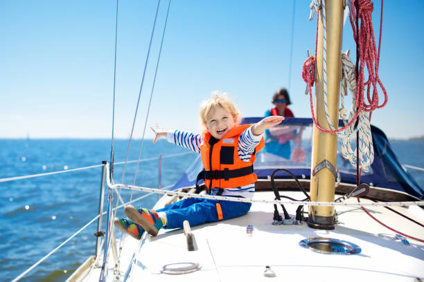 Kids sail on yacht in sea. Child sailing on boat. Kids sail on yacht in sea. Child sailing on boat. Little boy in safe life jackets travel on ocean ship. Children enjoy yachting cruise. Summer vacation for family. Young sailor on sailboat front deck. mast sailing photos stock pictures, royalty-free photos & images