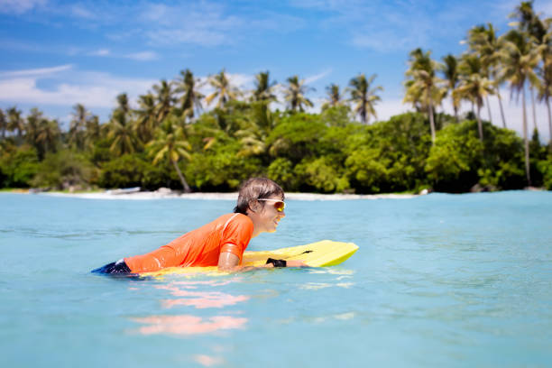 istock Child surfing on tropical beach. Surfer in ocean. 962353558