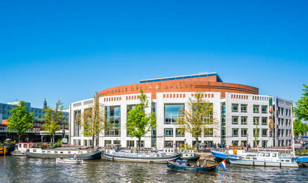 The river Amstel filled with small boats and the Stopera (opera building) in the background on a summer day Amsterdam, May 7 2018 - view on the river Amstel filled with small boats and the Stopera (opera building) in the background on a summer day stopera stock pictures, royalty-free photos & images